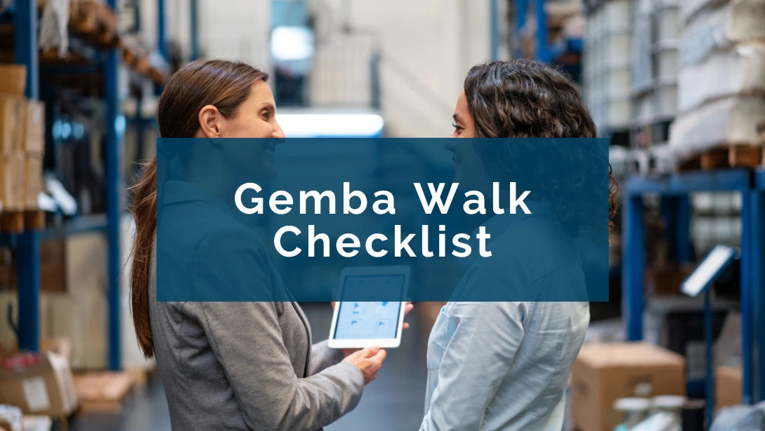 A manager holding a tablet in her hands and talking to an employee in a warehouse, both smiling