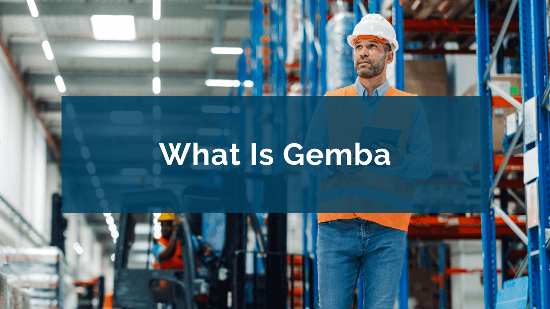 Worker wearing a helmet and safety vest, walking in a warehouse and observing in the distance, with a tablet in their hands