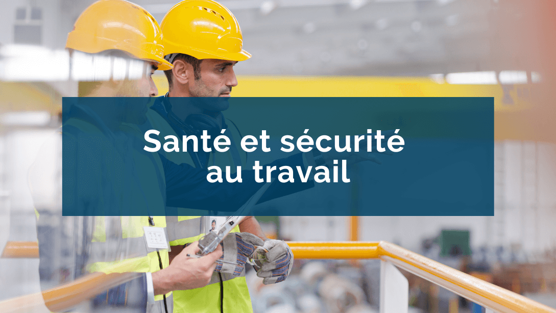 Un manager et un travailleur portant des casques et vestes de sécurité, le manager pointant et regardant au loin dans l'usine