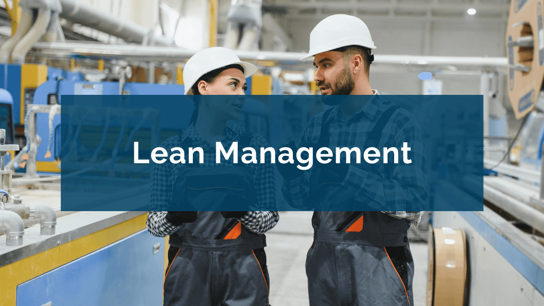 Deux travailleurs portant des salopettes et casques de sécurité, discutant dans une usine, l'air sérieux