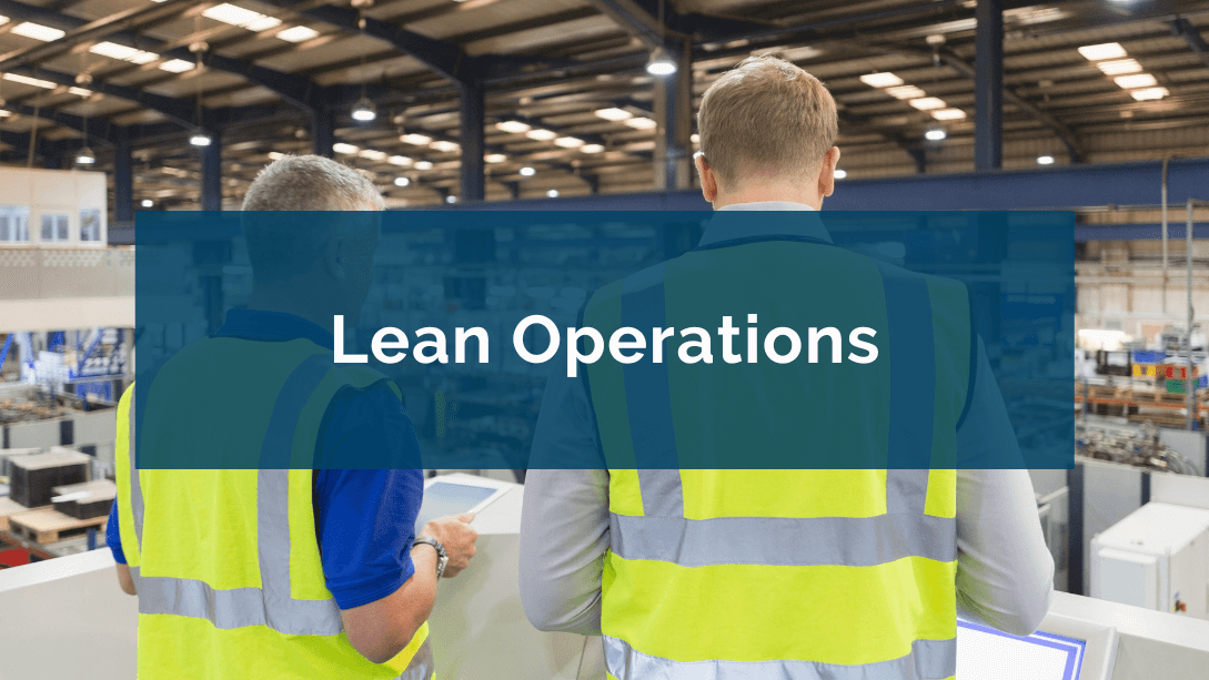 Two managers seen from behind, standing on a balcony and holding tablets, observing the production environment