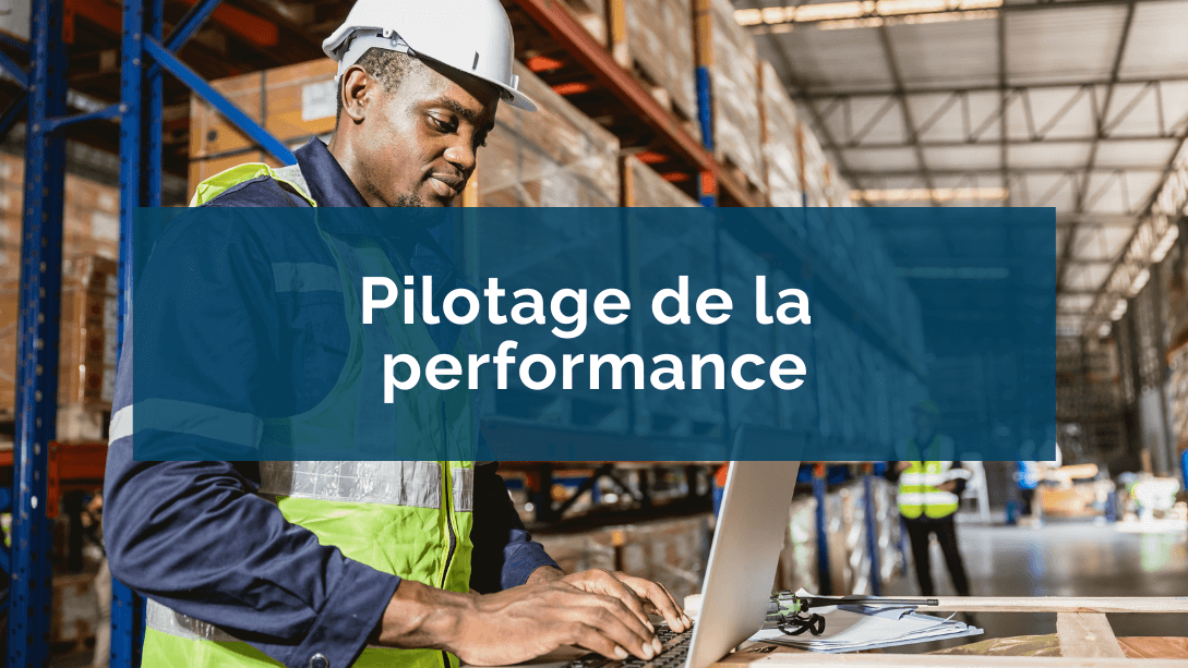 Vue rapprochée d'un travailleur portant un casque et une veste de sécurité, travaillant sur un portable, dans un entrepôt