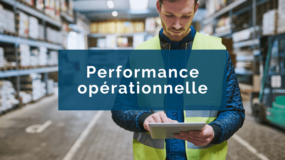 Travailleur portant une veste de sécurité, regardant et naviguant sur sa tablette, debout dans un entrepôt