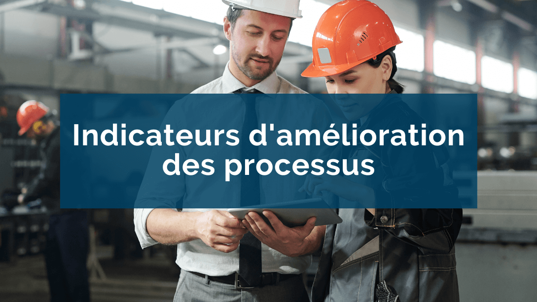 Un manager et une employée debout dans une manufacture, portant des casques de sécurité et regardant une tablette tenue par le manager