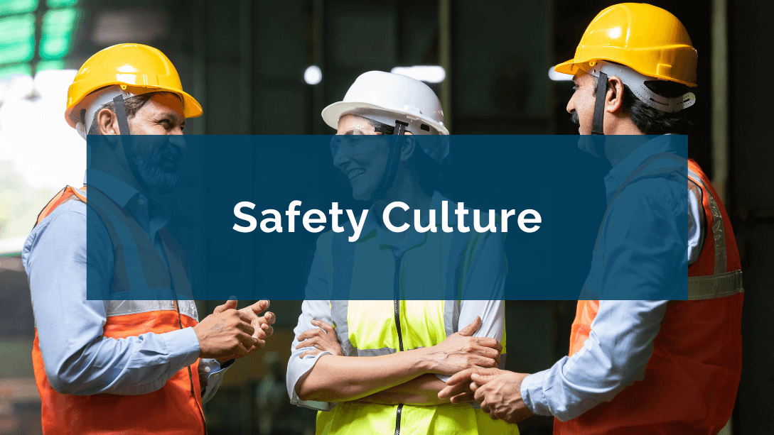 Three smiling colleagues wearing safety vests and hard hats, talking on a construction site